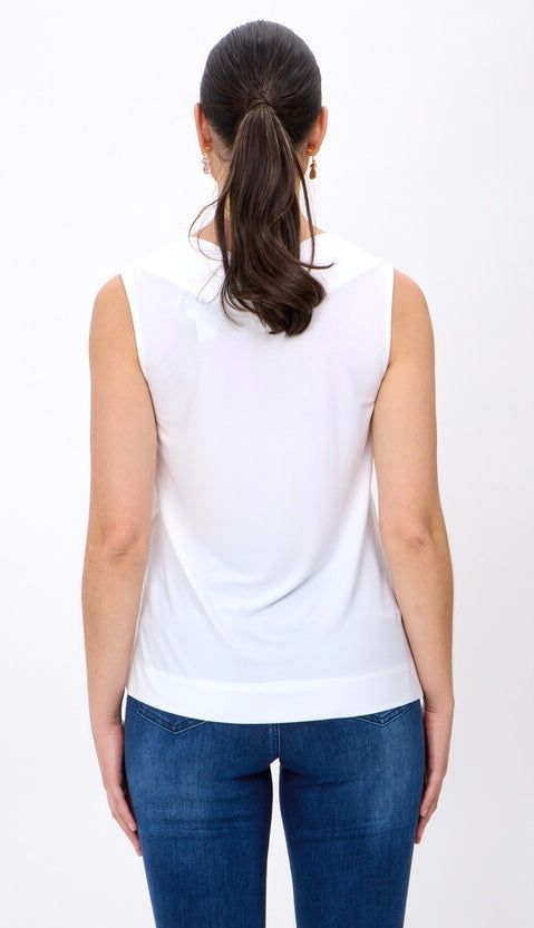 A woman viewed from the back wearing a white sleeveless top and blue jeans against a plain white background.