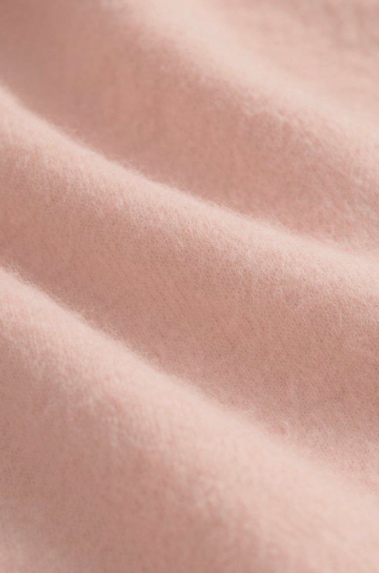 A close-up of soft blush pink fabric with gentle folds and a smooth, slightly nubby texture.