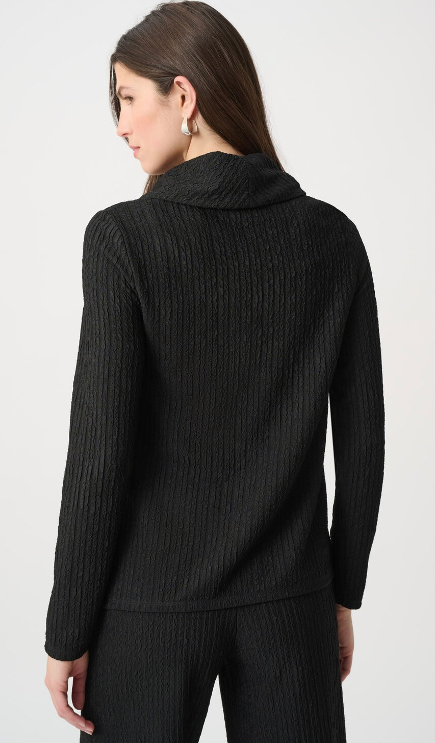 A woman shown from the back wearing a black ribbed knit mock neck sweater and matching pants against a light gray studio background.
