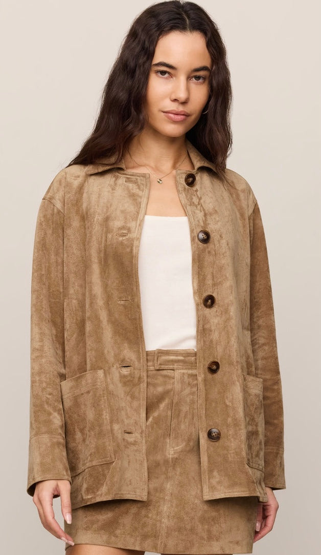 A woman modeling a tan suede-like button-front jacket with a matching mini skirt over a white top, photographed against a plain light beige studio background. -OLIVIA'S