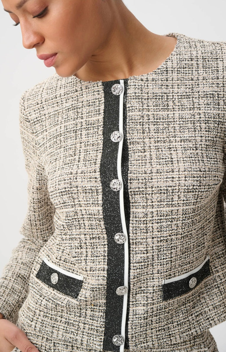 Close-up of a woman wearing a tweed jacket with a black glittery vertical placket, silver buttons, and matching black pocket flaps with silver button accents.
