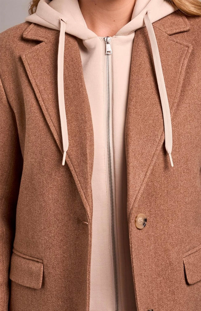 A close-up of a person wearing a brown textured coat over a light beige zip-up hoodie with cream drawstrings. - OLIVIA'S