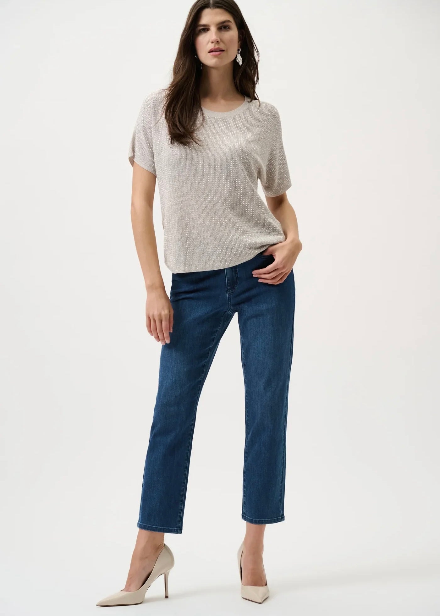 Woman wearing a light gray t-shirt and blue jeans on a white background