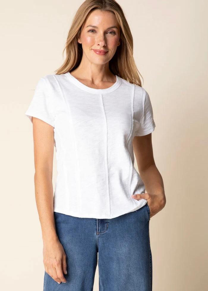 Woman wearing a white blouse and blue jeans against a beige background