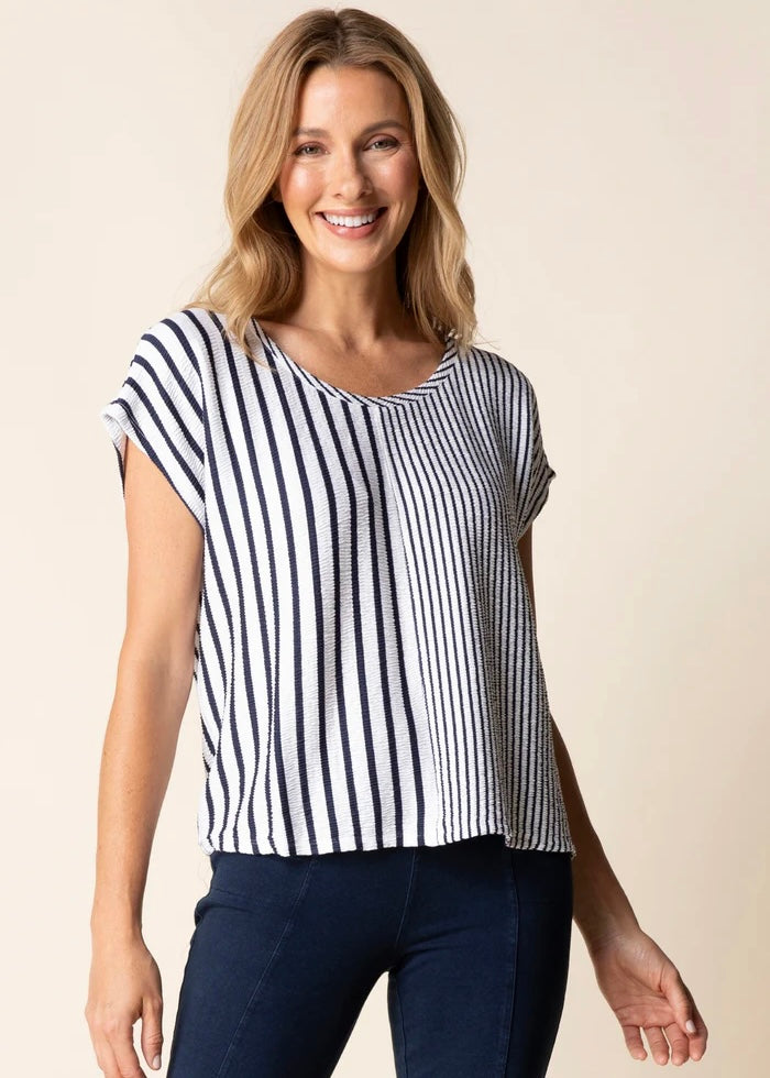 Woman wearing a black and white striped top with navy pants on a beige background