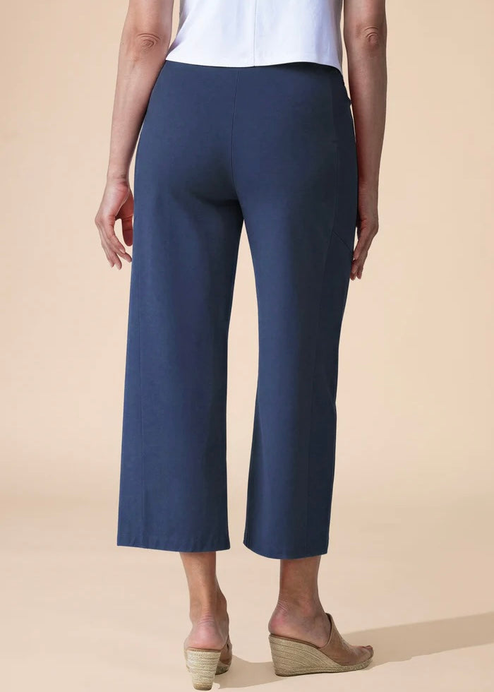 Person wearing navy blue pants on a beige background