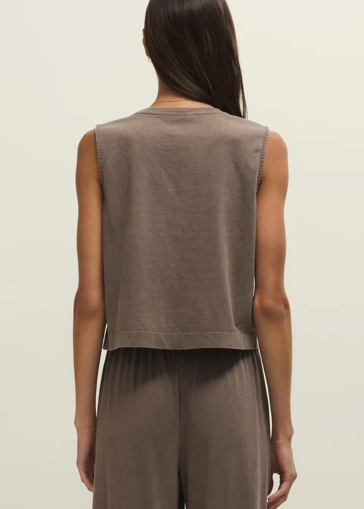 Woman wearing a brown sleeveless top and pants on a beige background