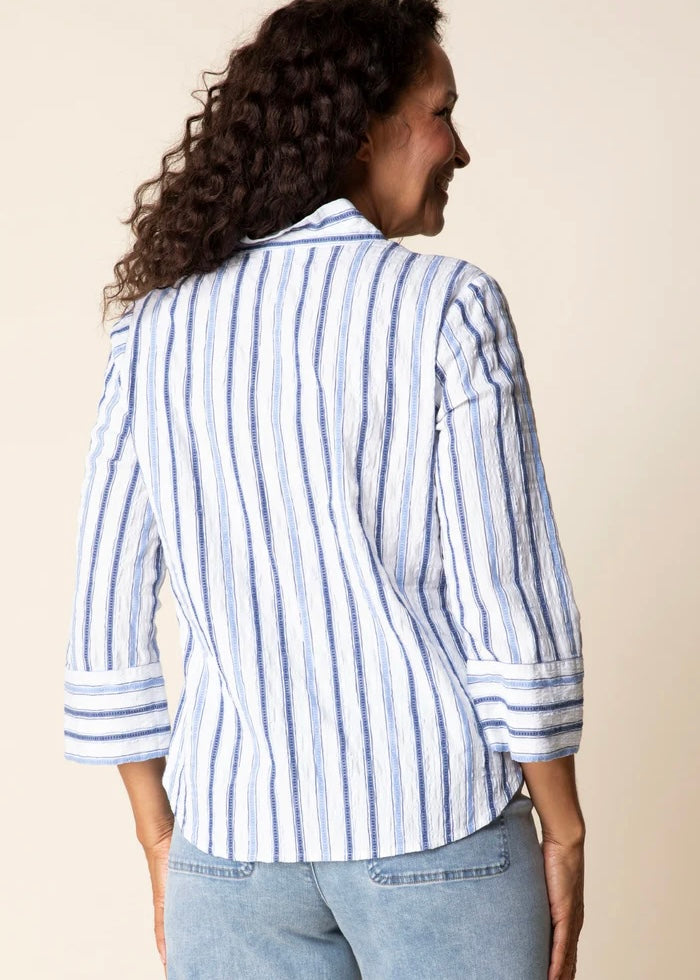 Person wearing a blue and white striped shirt against a beige background