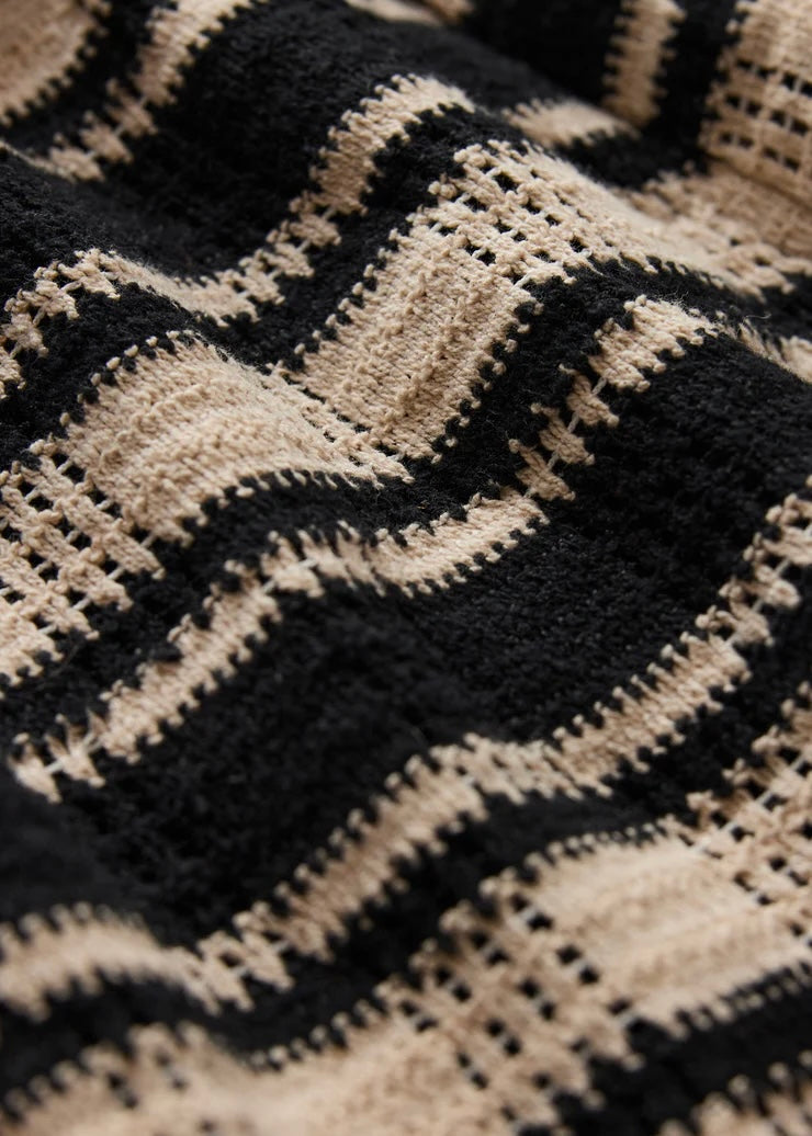 Close-up of a textured fabric with a geometric pattern in black and beige.