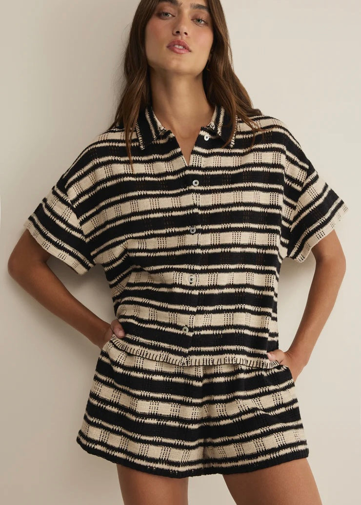 Woman wearing a black and white striped dress against a plain background
