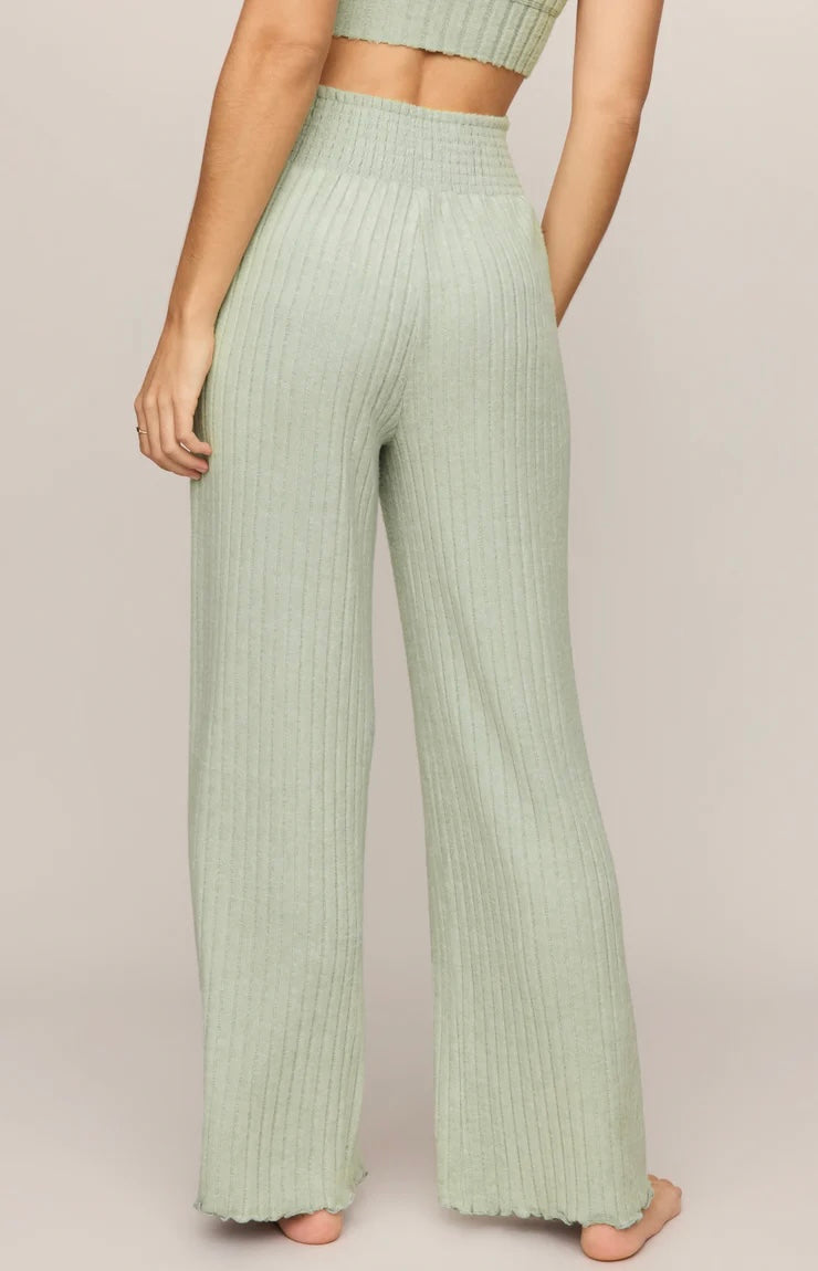 Person wearing light green ribbed pants on a plain background