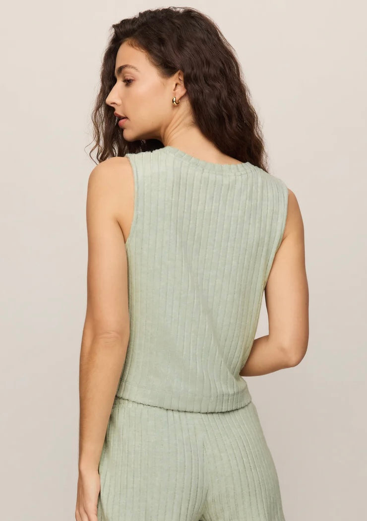 Woman wearing a light green ribbed sleeveless top and pants against a plain background