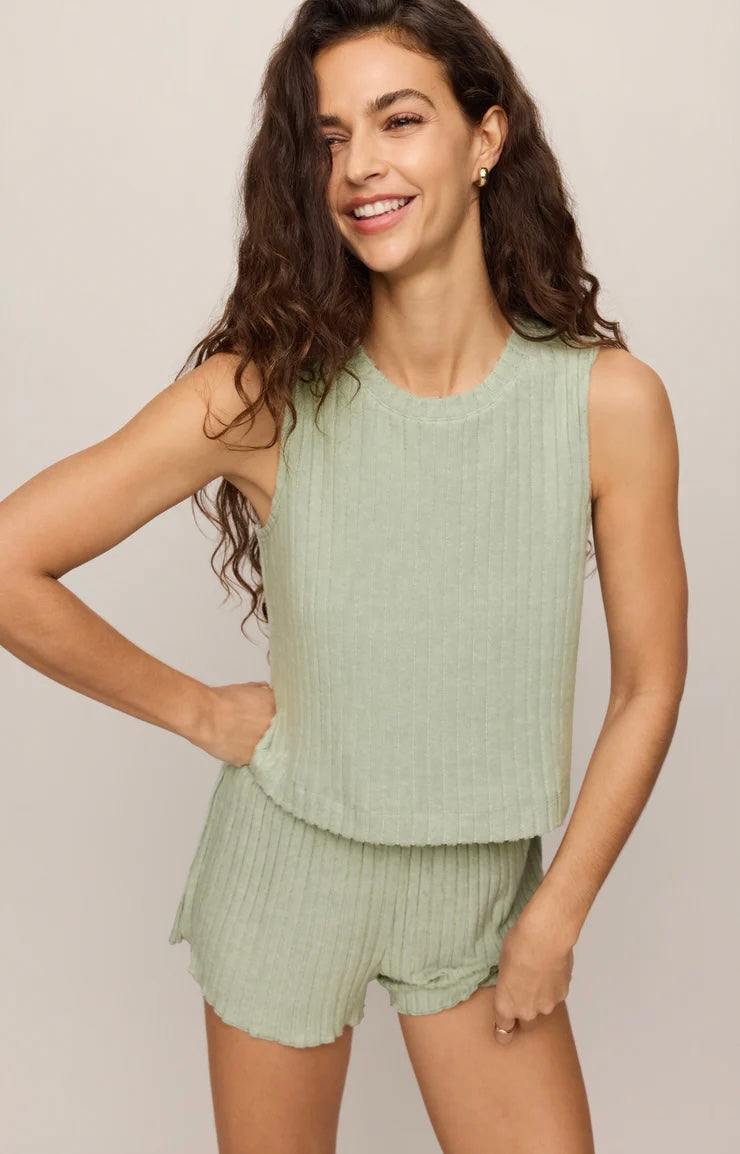 Woman wearing a light green sleeveless top and shorts on a plain background