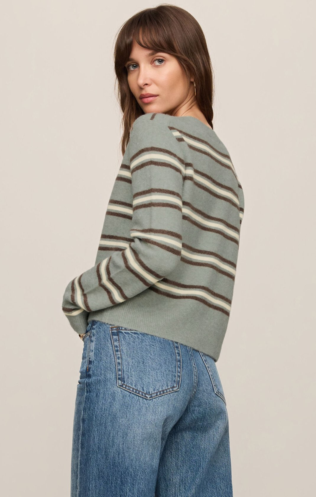 Woman wearing a striped sweater and jeans against a plain background