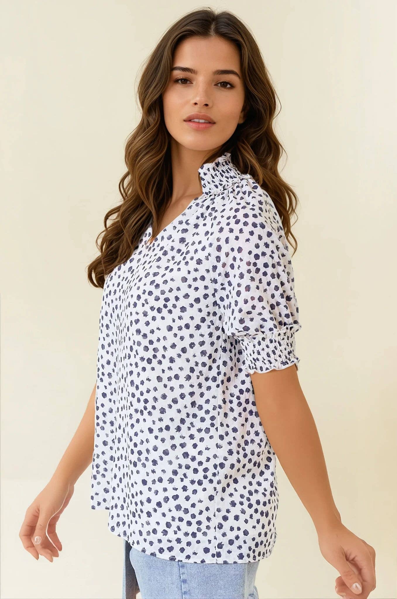Woman wearing a white blouse with black polka dots on a beige background