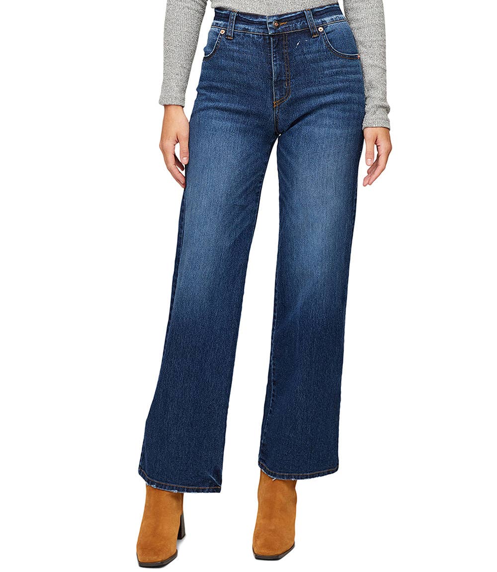 A model wearing a pair of dark blue wide-leg jeans with a faded wash, styled with a gray long-sleeve top and brown ankle boots against a white background.